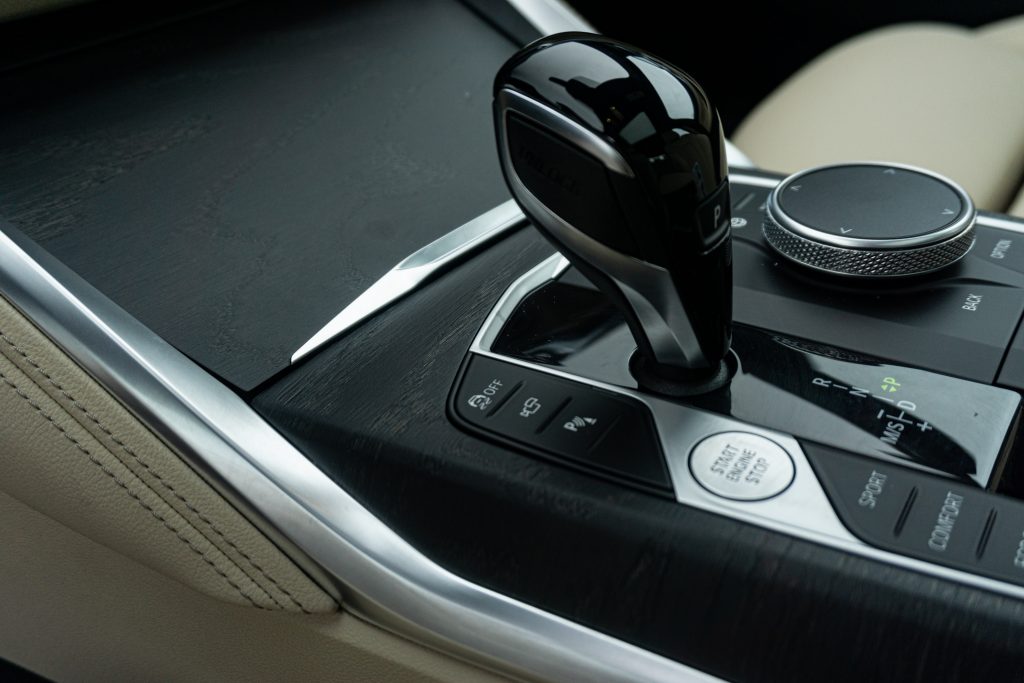 A close-up view of a 2022 BMW M440i xDrive Gran Coupe's shifter and black open-pore-wood-trimmed center console