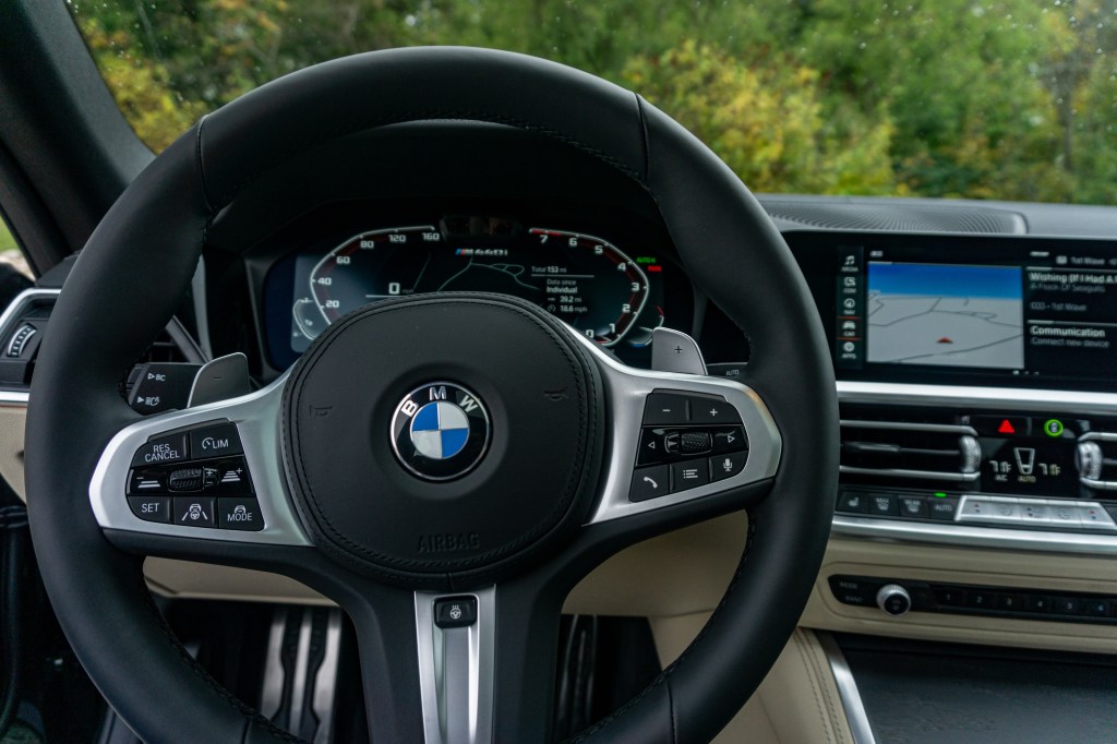 The center touchscreen, digital gauge cluster, and black-leather steering wheel of a 2022 BMW M440i xDrive Gran Coupe