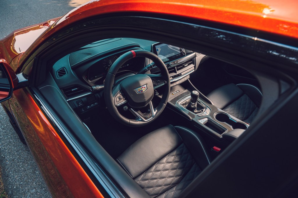 The black front seats and black dashboard of an orange 2022 Cadillac CT4-V Blackwing