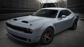 A chalk grey 2022 Dodge Challenger muscle car shot from the front 3/4 in a warehouse