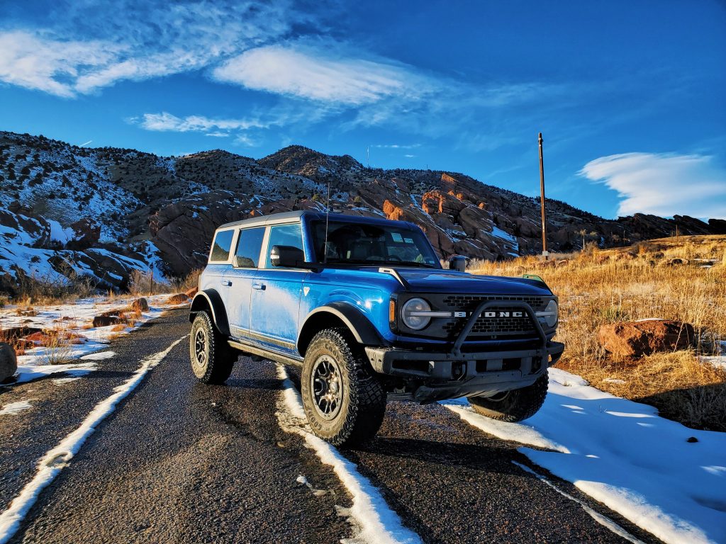 A blue 2022 Ford Bronco compact SUV shot from the front 3/4 at Colorado's Red Rocks.