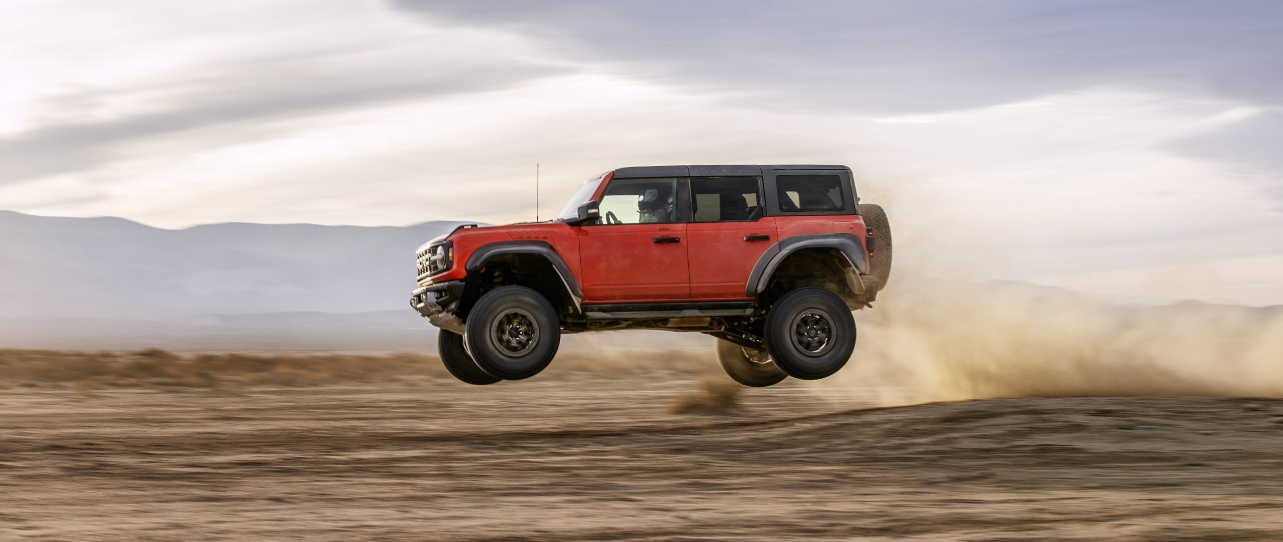 A profile shot of a mid-air Ford Bronco Raptor in orange