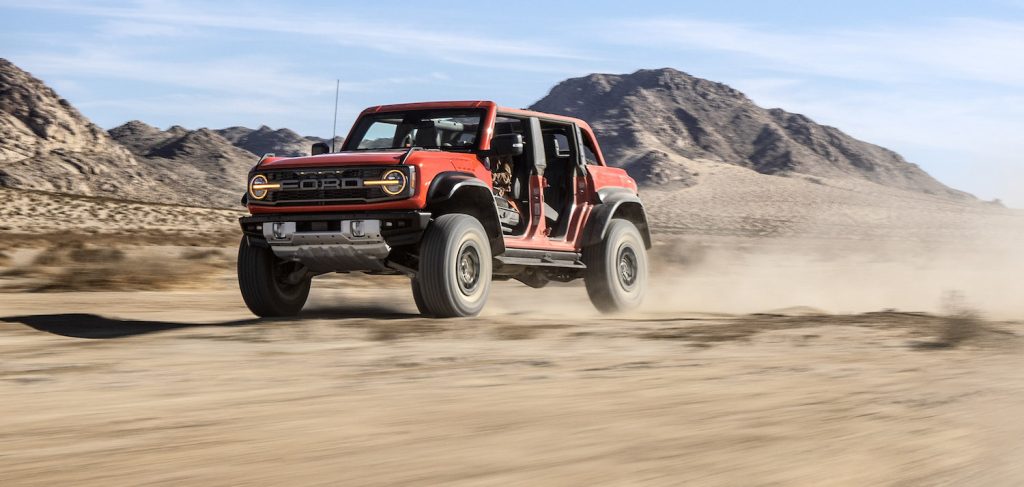 Orange 4x4 SUV speeding across the desert