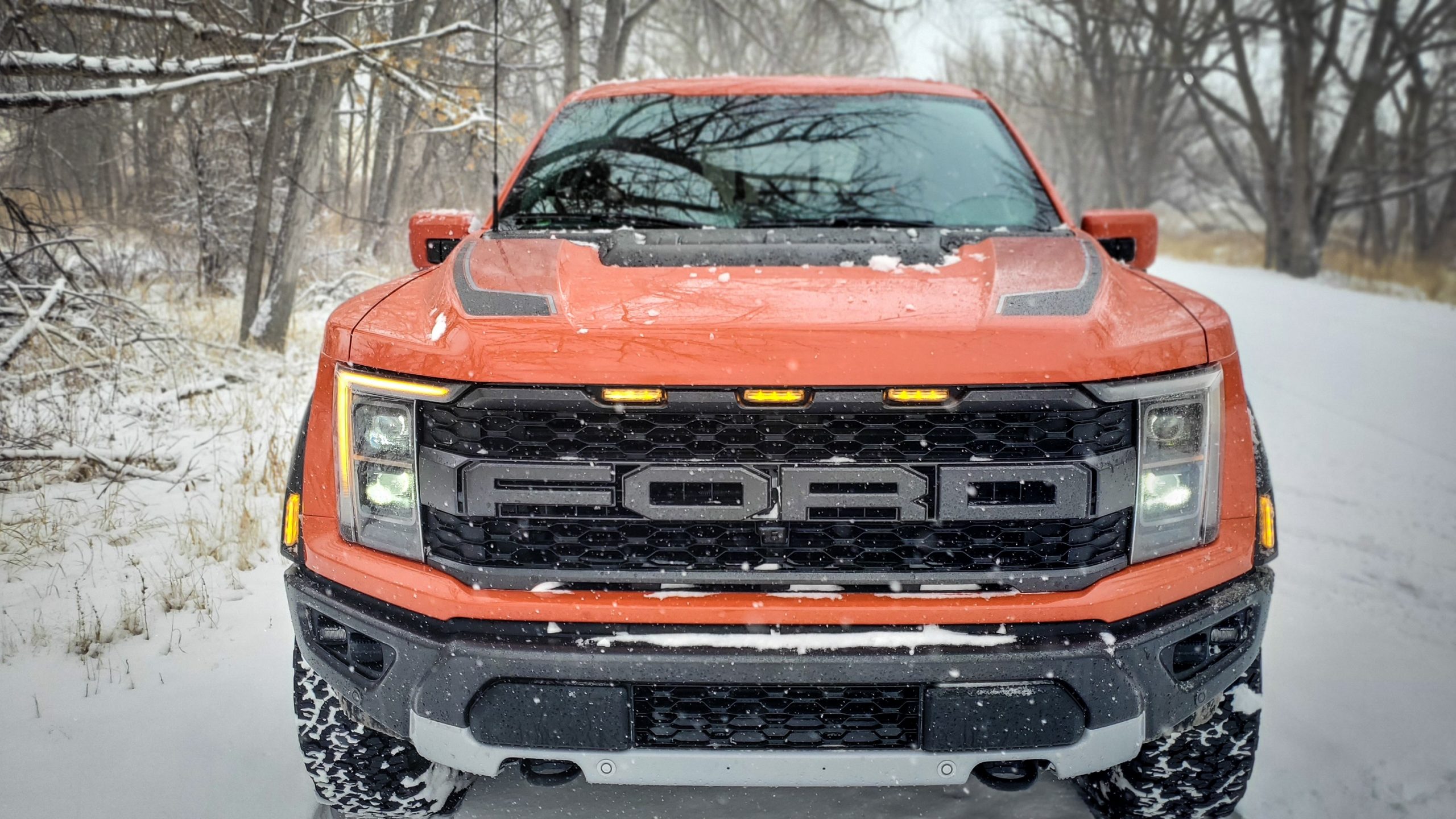 A front shot of an F-150 Raptor in orange during a snow storm