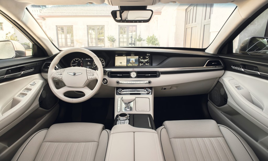 The white-leather-upholstered front seats and wood-trimmed dashboard of a 2022 Genesis G90
