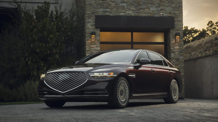 A maroon 2022 Genesis G90 in front of a house