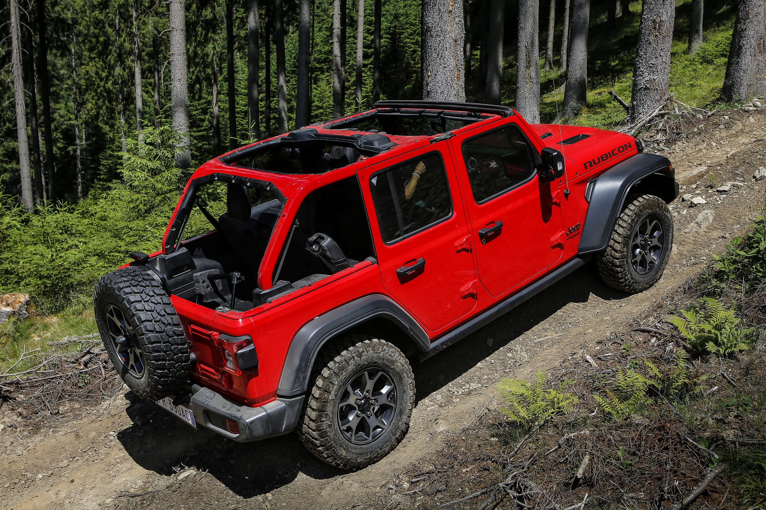 A red Jeep Wrangler Rubicon shot from the rear 3/4 on an off-road trail