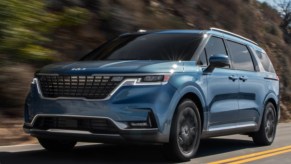 A blue 2022 Kia Carnival in the woods.
