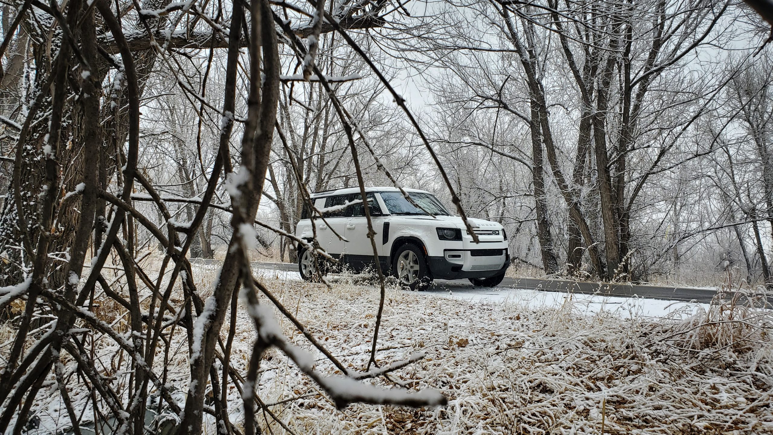 A white 2022 Land Rover Defender shot from the front 3/4 on a snowy backroad
