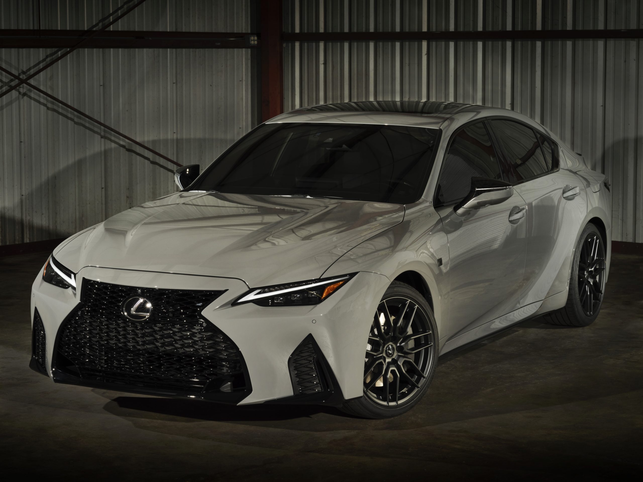A chalk grey 2022 Lexus IS 500 shot from the front 3/4 in a warehouse