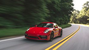 A 'Carmine Red' 2022 Porsche 911 Carrera GTS drives down a forest road