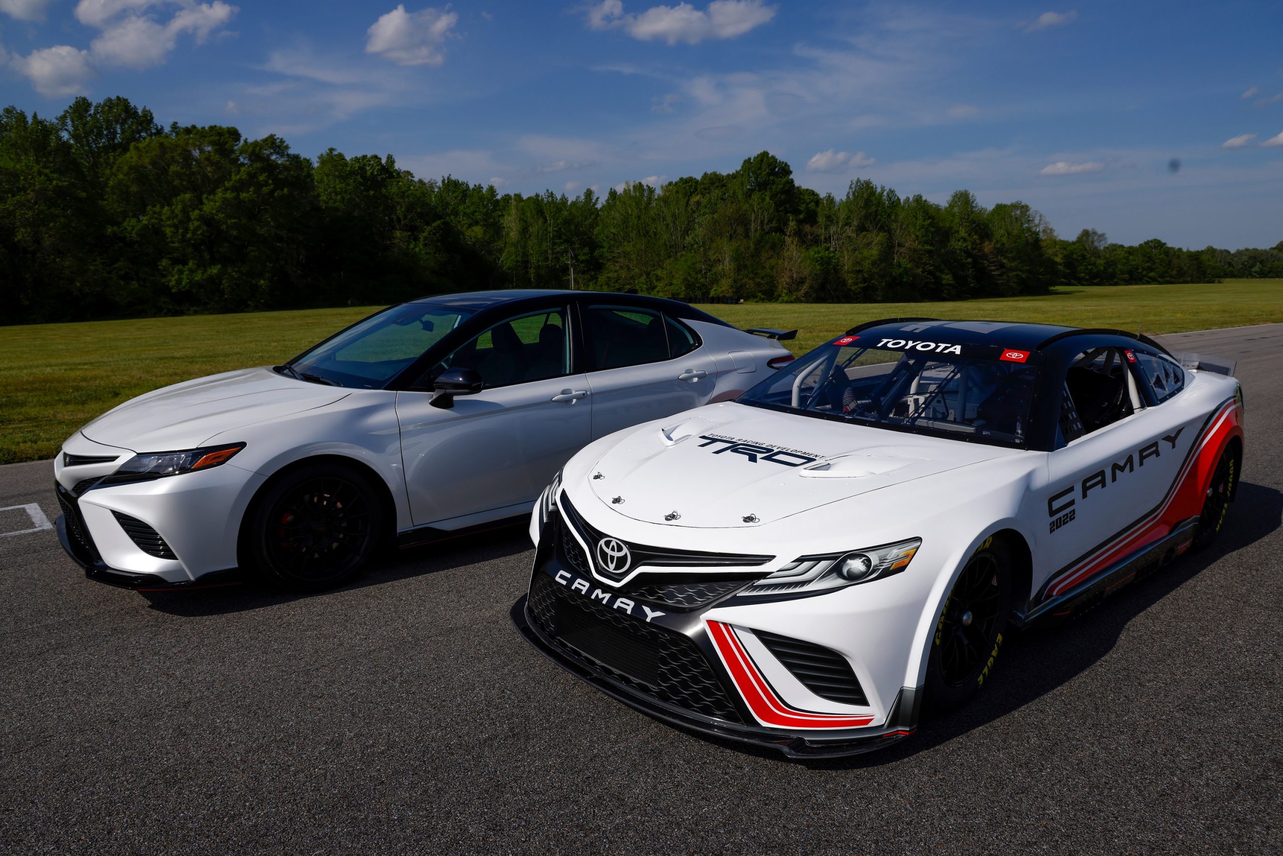A white TRD Camry next to the brand's stock car for NASCAR competition