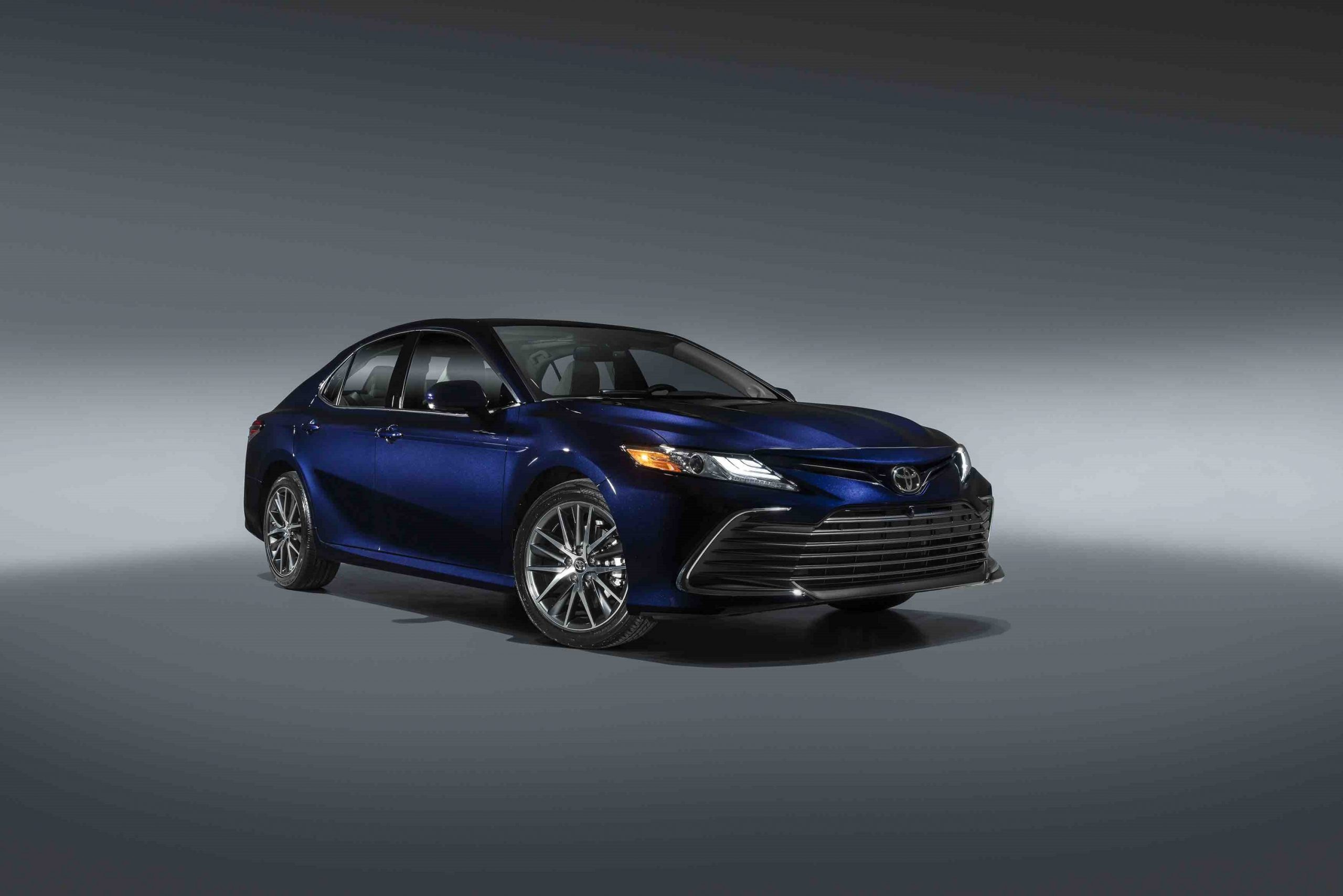 A blue Camry Hybrid shot from the front 3/4 in a photo booth