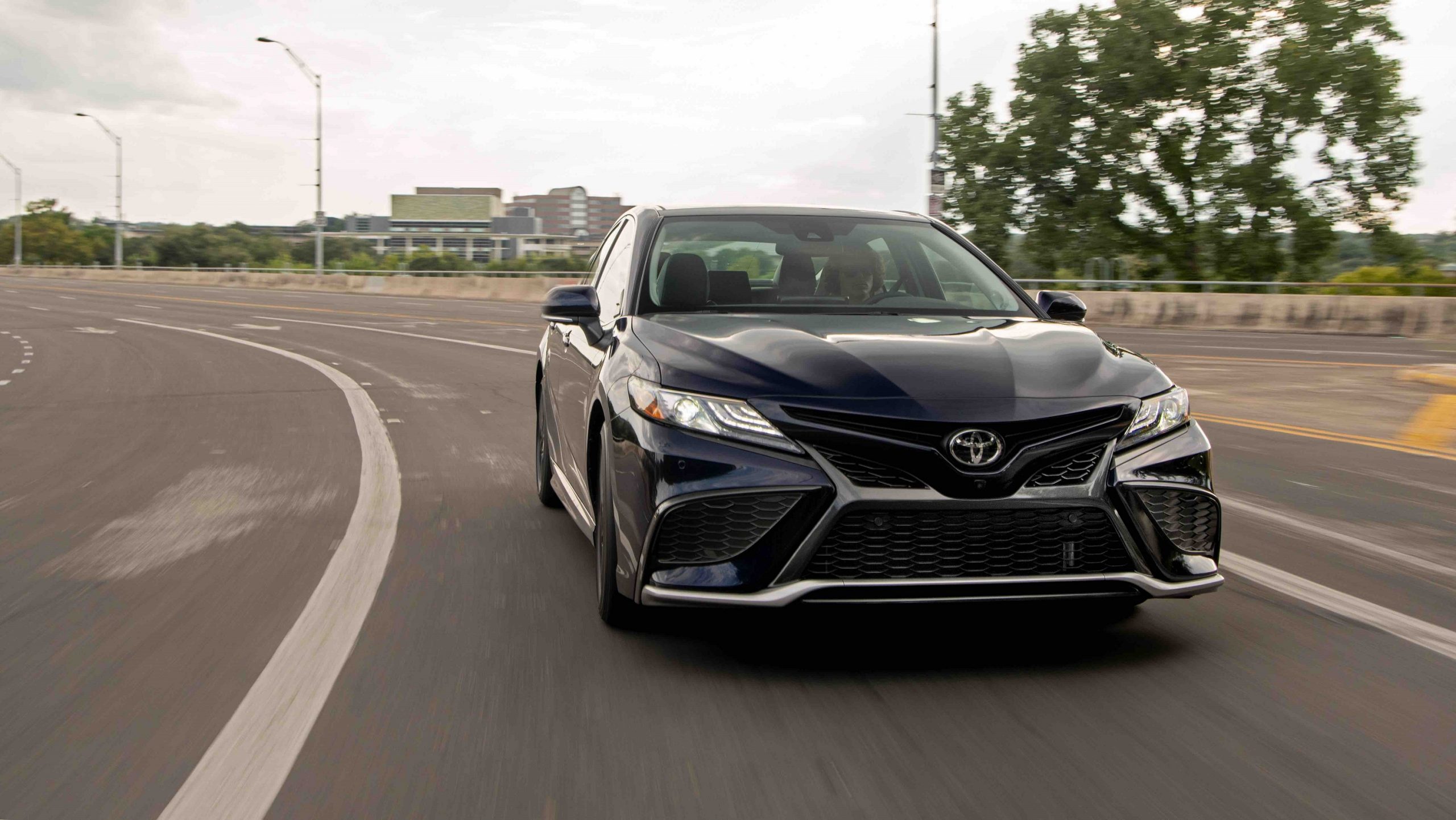 A black 2022 Toyota Camry shot from the front on a highway