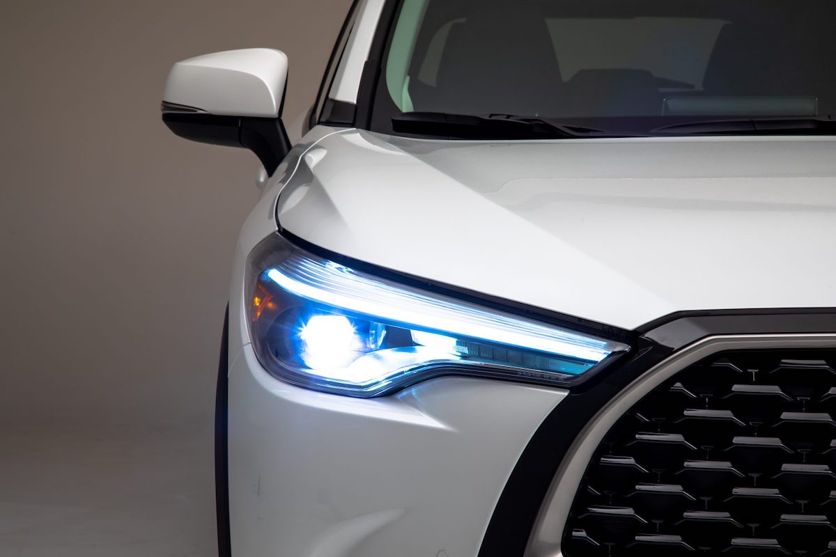 A white 2022 Toyota Corolla Cross SUV's right grille, headlight, and side mirror