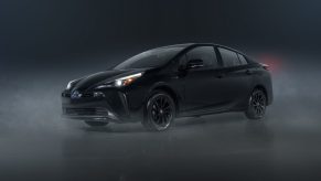 A black 2022 Toyota Prius with AWD shot from the front 3/4 in a dark photo studio