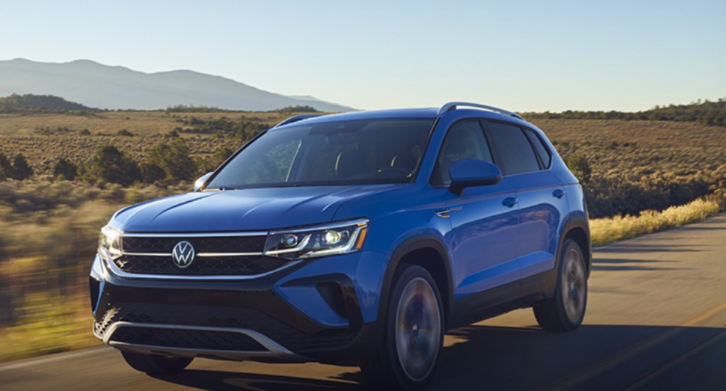 A blue 2022 Volkswagen Taos subcompact SUV is driving on the road. 
