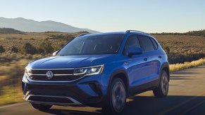 A blue 2022 Volkswagen Taos subcompact SUV is driving on the road.