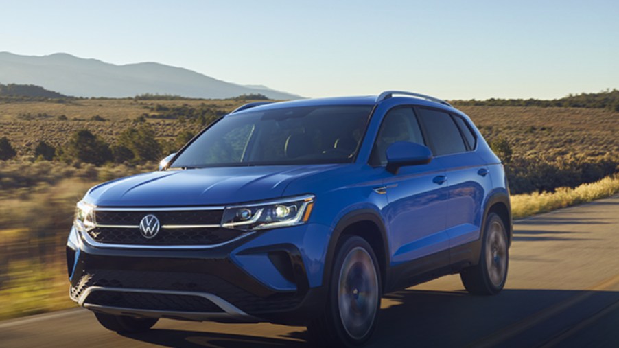 A blue 2022 Volkswagen Taos subcompact SUV is driving on the road.