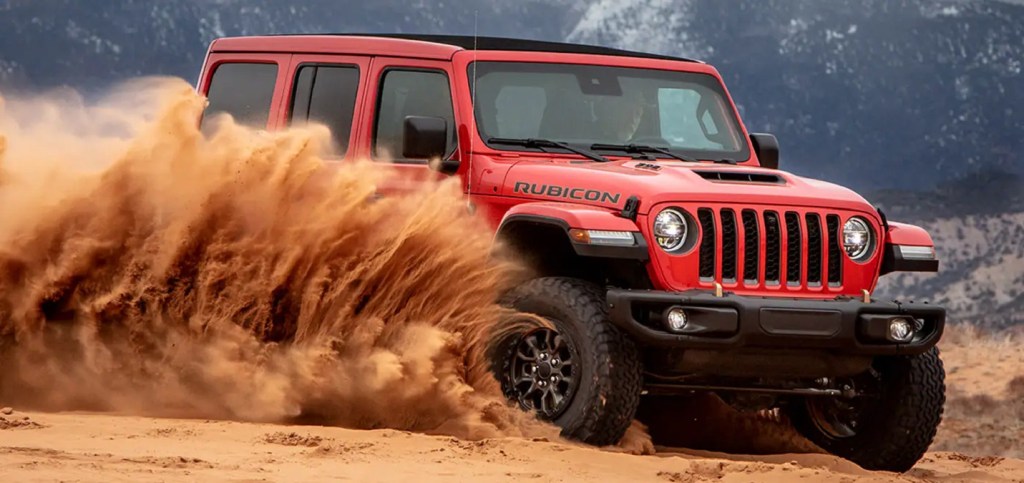 A red 2022 Jeep Wrangler spraying dirt. 