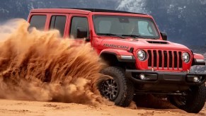 A red 2022 Jeep Wrangler spraying sand.
