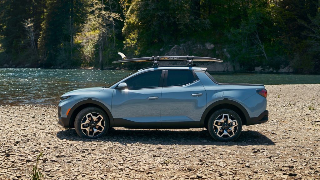 2022 Hyundai Santa Cruz parked next to some water with surfboards on top.