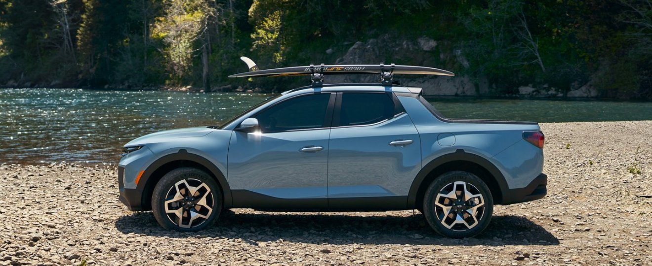 2022 Hyundai Santa Cruz parked next to some water with surfboards on top.