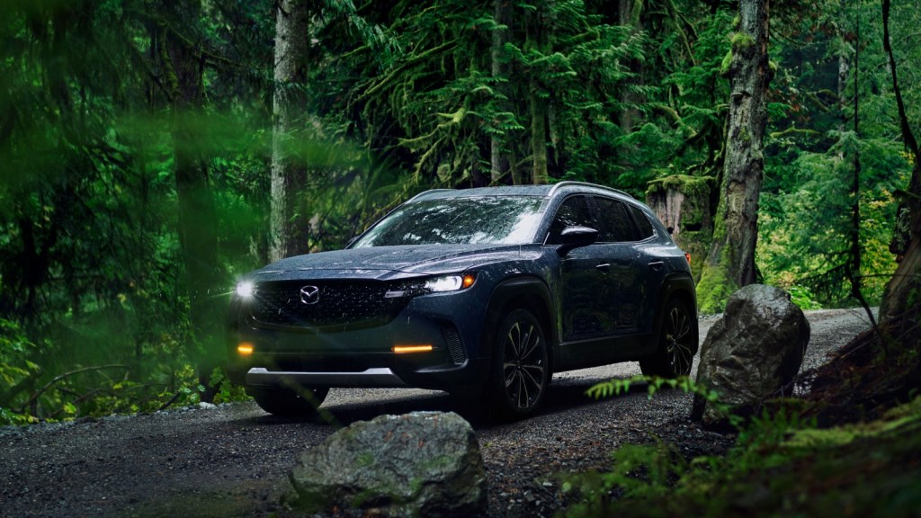 A dark blue Mazda CX-5 driving through the forest.