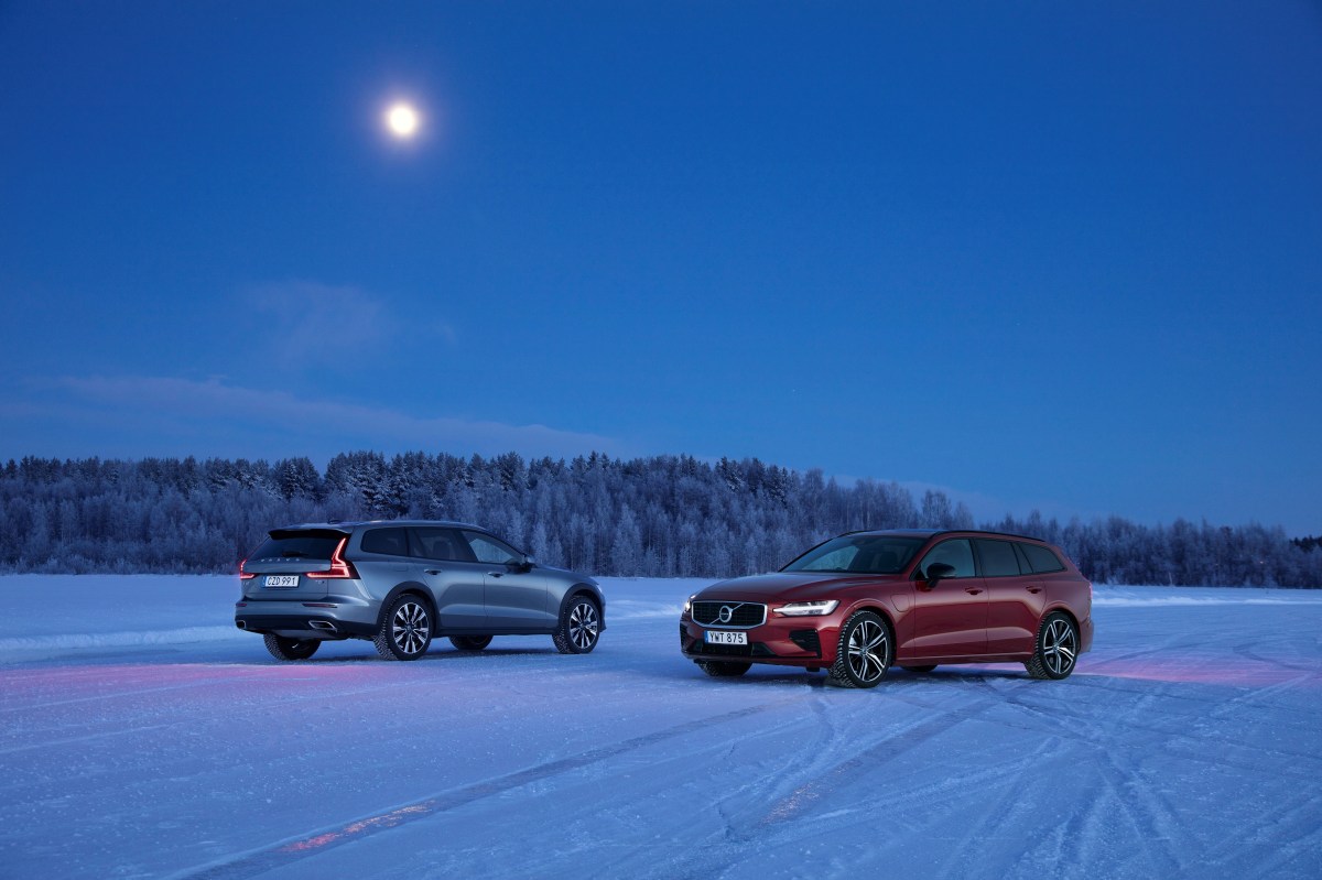 A grey Volvo V60 Cross Country sits next to a red Volvo V60 T8 on a snow and ice-covered lake.
