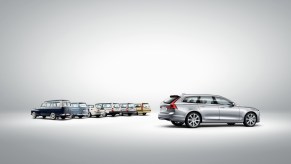 A profile view of a silver Volvo V90 with several older Volvo wagon models.