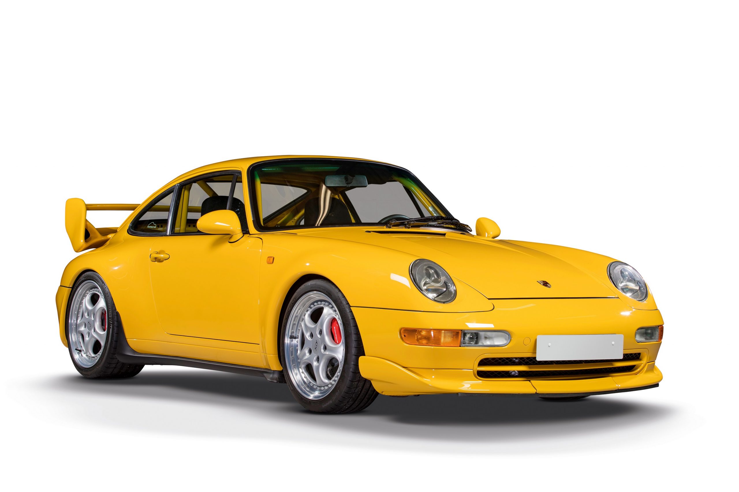 A yellow 993 Porsche 911 shot from the front 3/4 in a photo booth