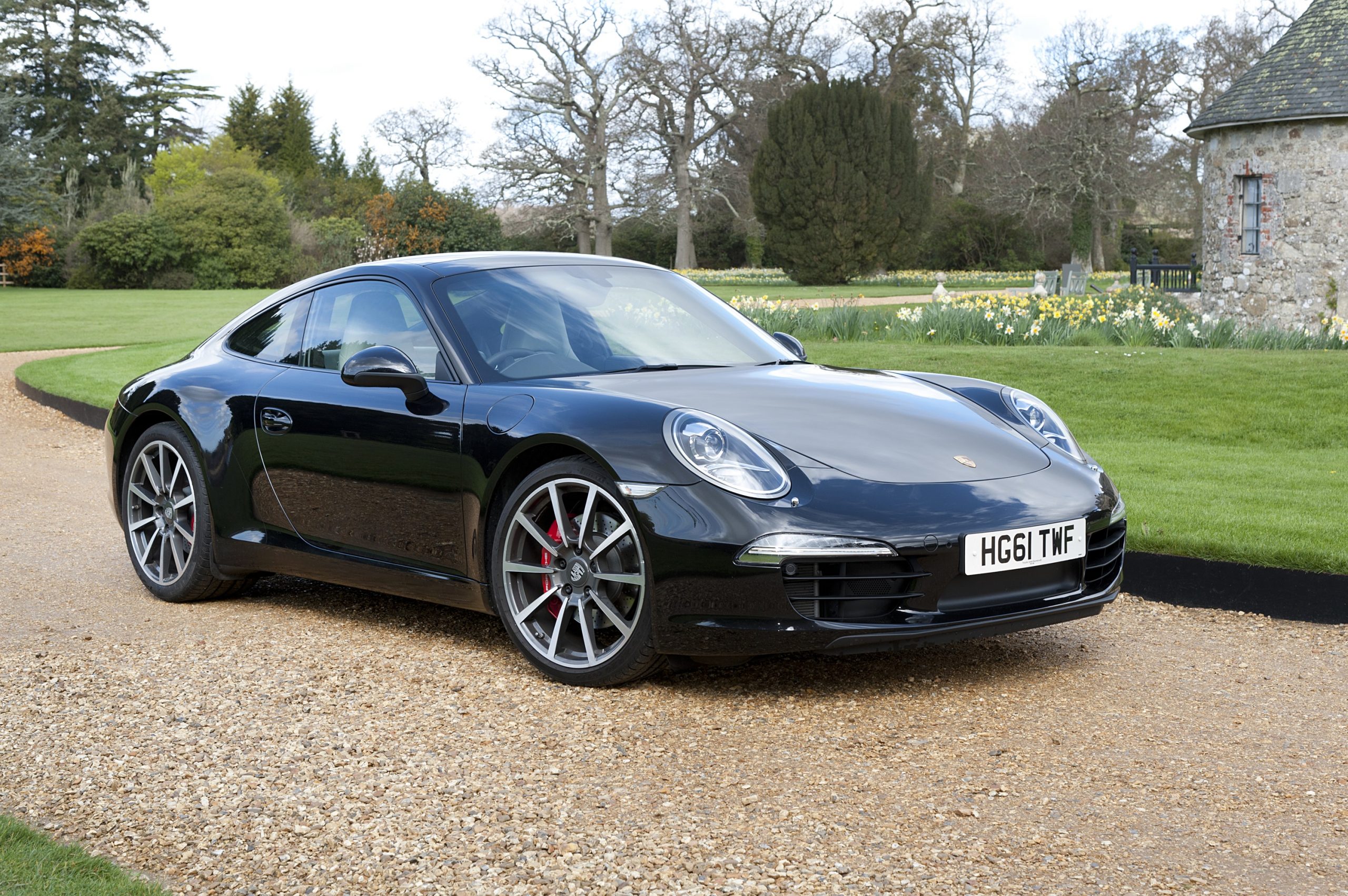 A black 997 Porsche 911 Carrera shot from the front 3/4 on a gravel drive
