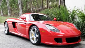 A Guards Red Porsche Carrera GT parked on a tree-lined drive