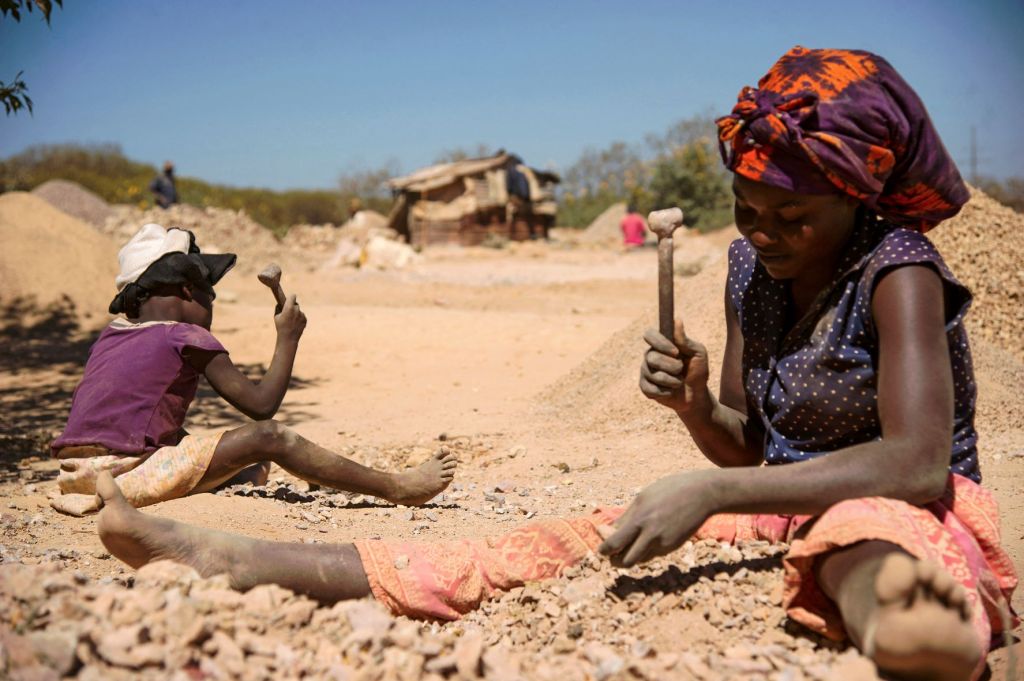 A child and a woman break rocks from a cobalt mine in the DRC