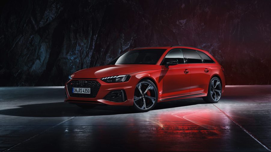 A 3/4 front view of a red 2022 Audi RS4 Avant parked in front of a dark rock wall