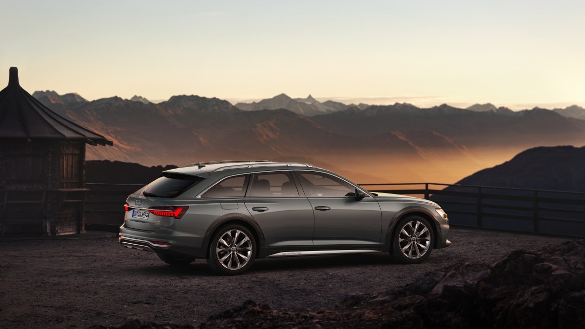 A profile view of a grey Audi A6 Allroad with mountains in the background.