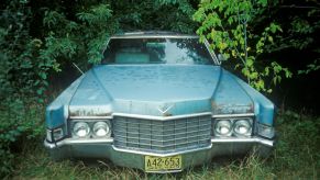 A blue abandoned car in the woods.