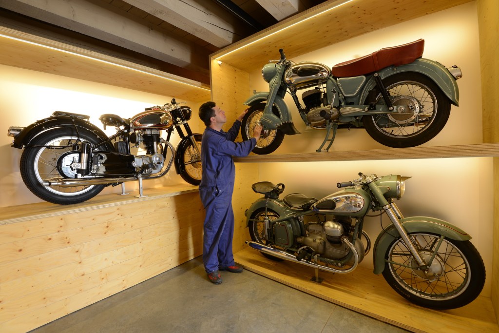 A blue-clad Einbecker Kulturstiftung Kornhaus Collection curator inspects several classic Horex motorcycles