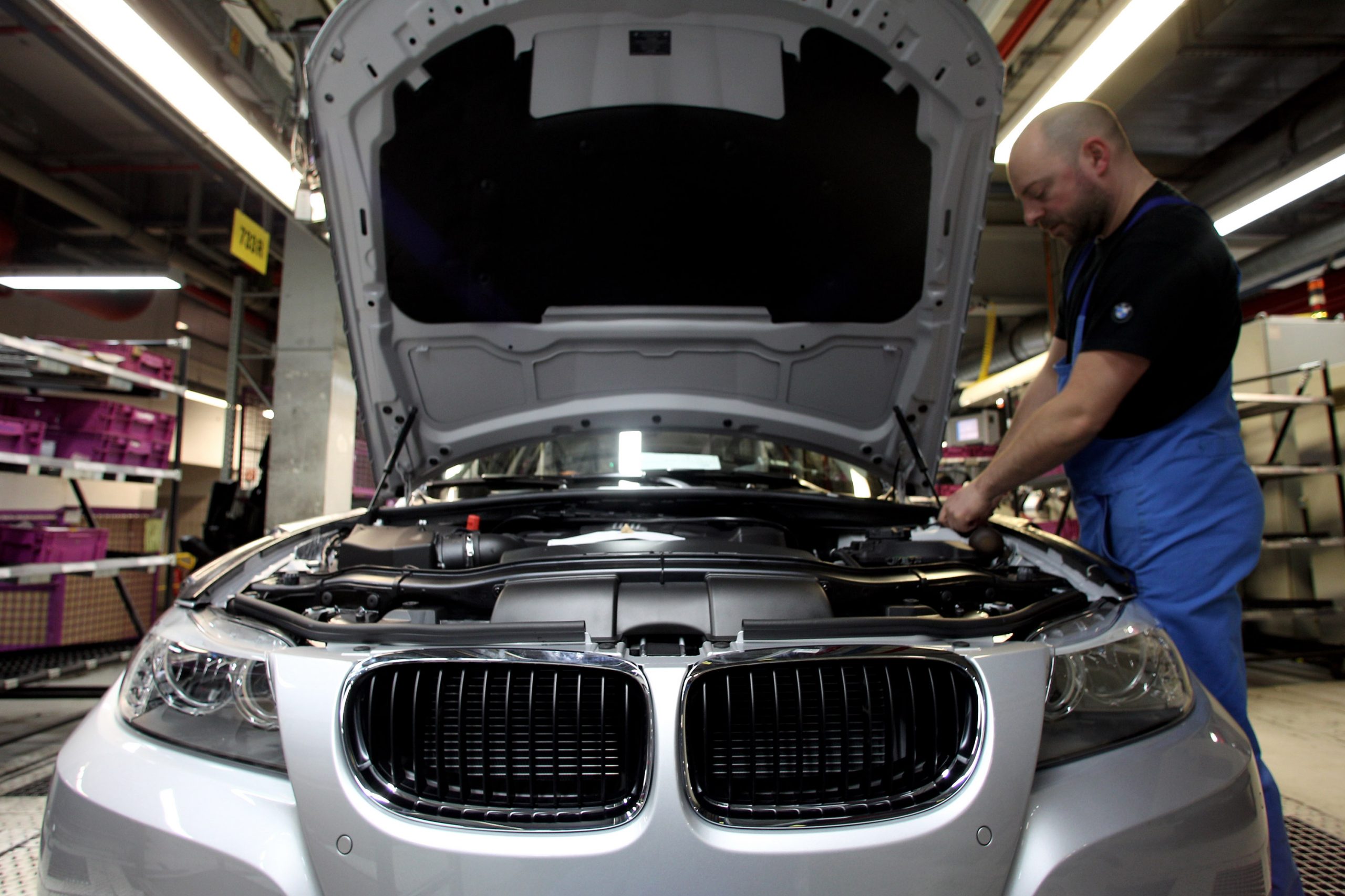 A mechanic works on a BMW 3 Series sedan in a shop