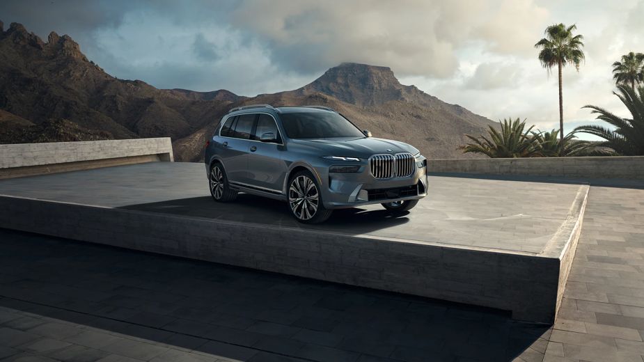 The 2023 BMW X7 drives to the right on the screen in a dry mountainous area.