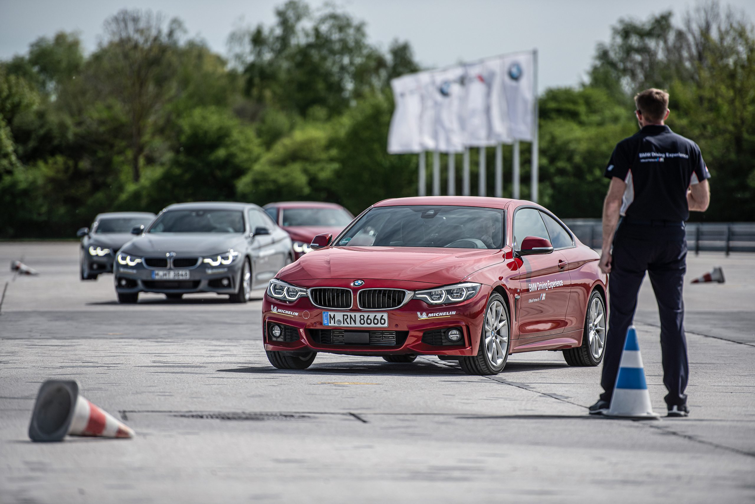 An instructor at the BMW Performance Driving School directs cars through a series of cones