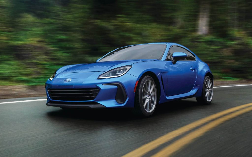 Blue 2022 Subaru BRZ, one of the most affordable sports cars, driving by a forest