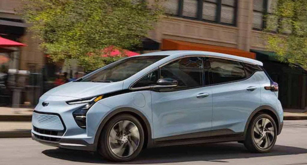 A blue Chevy Bolt electric vehicle is driving on the road. 