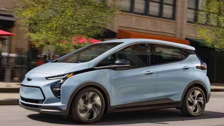 A light blue 2022 Chevy Bolt electric vehicle is driving on the road.