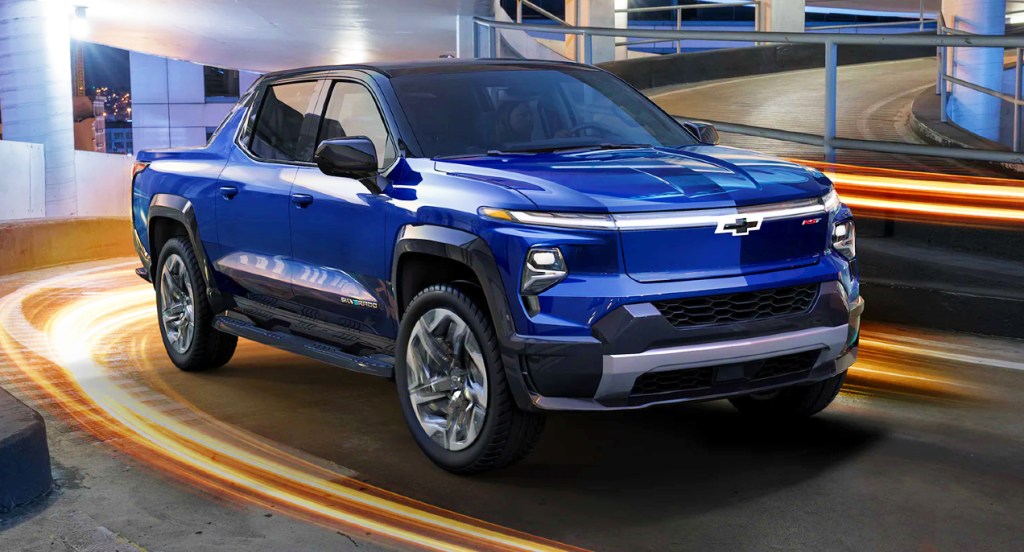 A blue 2022 Chevy Silverado EV is driving up a parking complex.