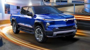 A blue 2022 Chevy Silverado EV is driving up a parking complex.