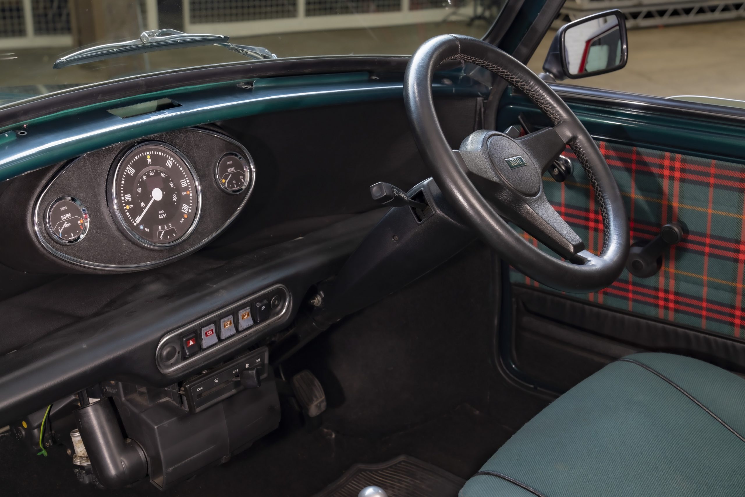 The interior of Mini's EV-swapped Cooper with plaid door inserts and green cloth seats