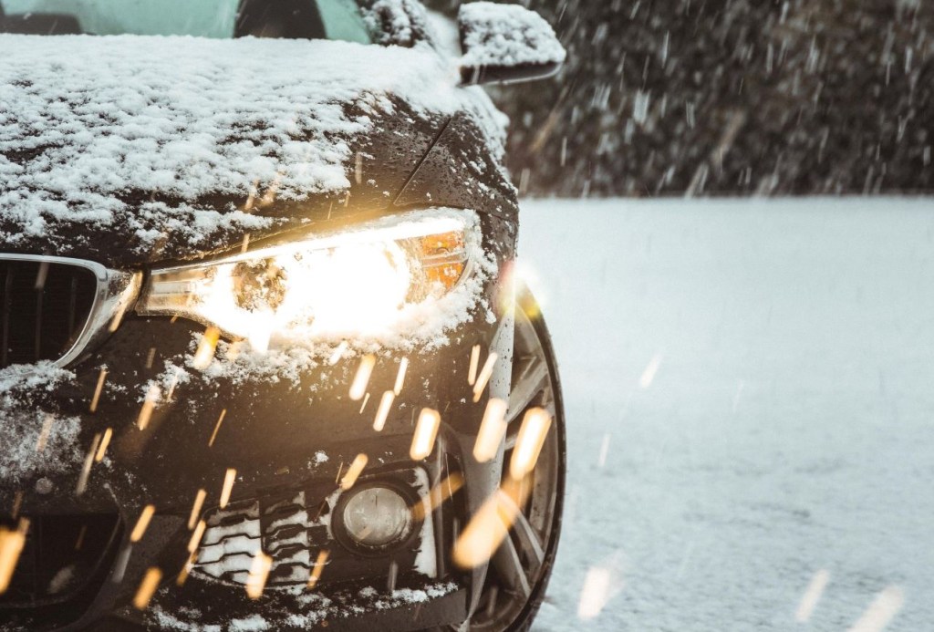 Close-up view of car headlights shining in snowy weather