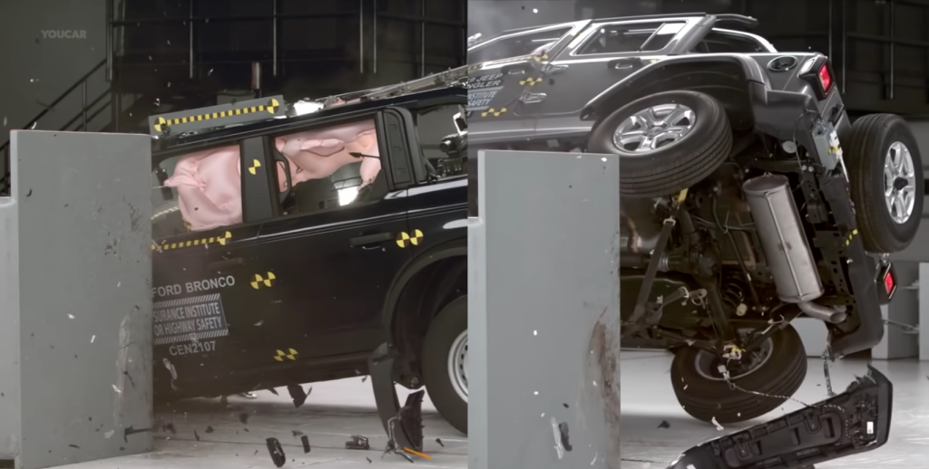 The Ford Bronco and Jeep Wrangler crash test lined up next to each other showing the Jeep mostly off the ground while the Bronco is on all four.