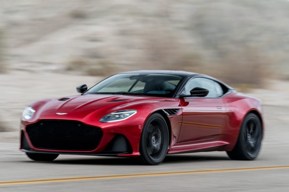 A red Aston Martin DBS driving fast on a road